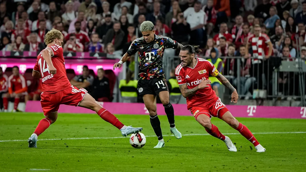 Luis Díaz bedrängt von zwei Gegenspielern während des Bundesligaspiels zwischen dem FC Bayern und Union Berlin