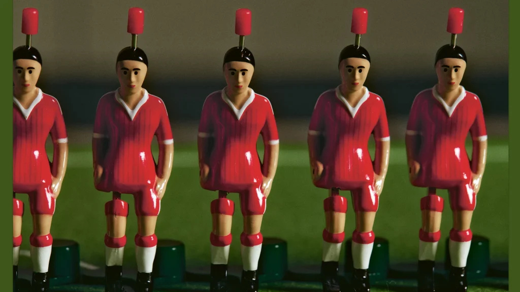 Five red table football figures lined up in a row