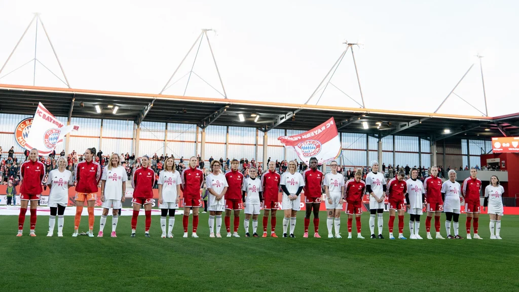 FC Bayern Women’s starting XI before a Bundesliga match, alongside women affected by breast cancer
